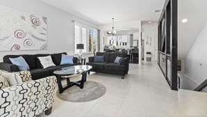Una sala de estar moderna con un conjunto de sofá, una mesa de centro de vidrio y un cuadro abstracto grande en la pared.