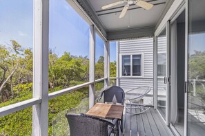 A covered outdoor area with a table and chairs, large windows, and a ceiling fan.