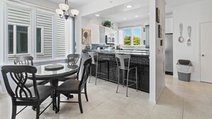 Una cocina moderna con una isla central, taburetes de bar y una mesa de comedor con sillas.
