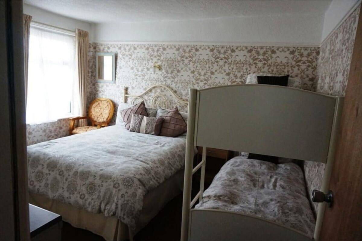 A bedroom with two beds, a chair, and a window.