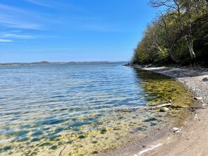 A clear lake with a sandy beach and trees along the shore. - Holla die Boddenfee @Höfthus 68 m², private entrance, terrace with thatched roof, ocean view (Middelhagen)