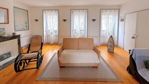 Una camera da letto con un letto, una sedia, un termosifone e una finestra con tende.