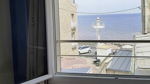 Una stanza con un'ampia finestra che si affaccia su una zona costiera, con un edificio con una cupola bianca e vista sul mare.