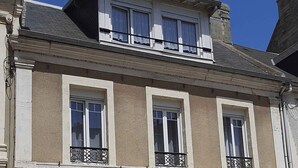 Un edificio a due piani con facciata beige, finestre con cornice bianca e un balcone con ringhiere in ferro battuto.