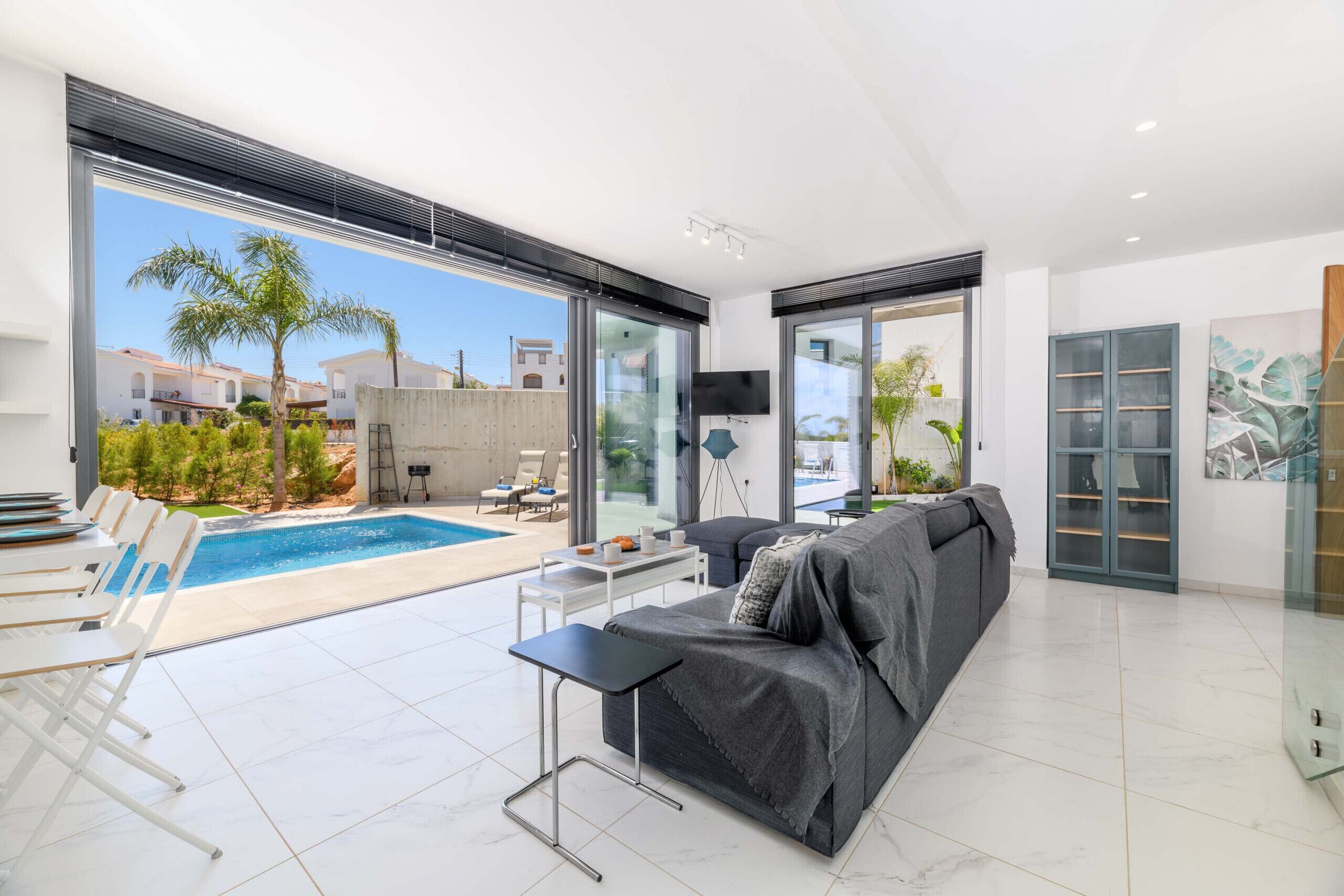 Ein modernes Wohnzimmer mit einer großen Couch, einem Couchtisch und Blick auf einen Pool.