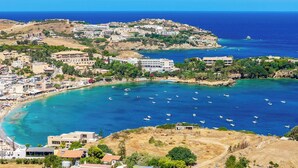 A coastal town with buildings along the shoreline, boats in the water, and a clear view of the sea. - Villa Paradiso Tria - Two Bedroom Villa, Sleeps 4 (Malevizi)