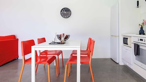 A modern kitchen with white appliances, a dining table with red chairs, and a wall clock. - Villa Paradiso Tria - Two Bedroom Villa, Sleeps 4 (Malevizi)