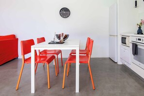 A modern kitchen with white appliances, a dining table with red chairs, and a wall clock. - Villa Paradiso Tria - Two Bedroom Villa, Sleeps 4 (Malevizi)