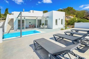 A modern outdoor pool area with lounge chairs, a staircase leading to a covered patio, and a clear blue sky. - Villa Paradiso Tria - Two Bedroom Villa, Sleeps 4 (Malevizi)