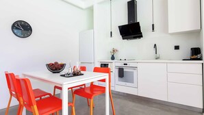 A modern kitchen with white cabinets, a black microwave, and a dining area with a white table and red chairs. - Villa Paradiso Tria - Two Bedroom Villa, Sleeps 4 (Malevizi)