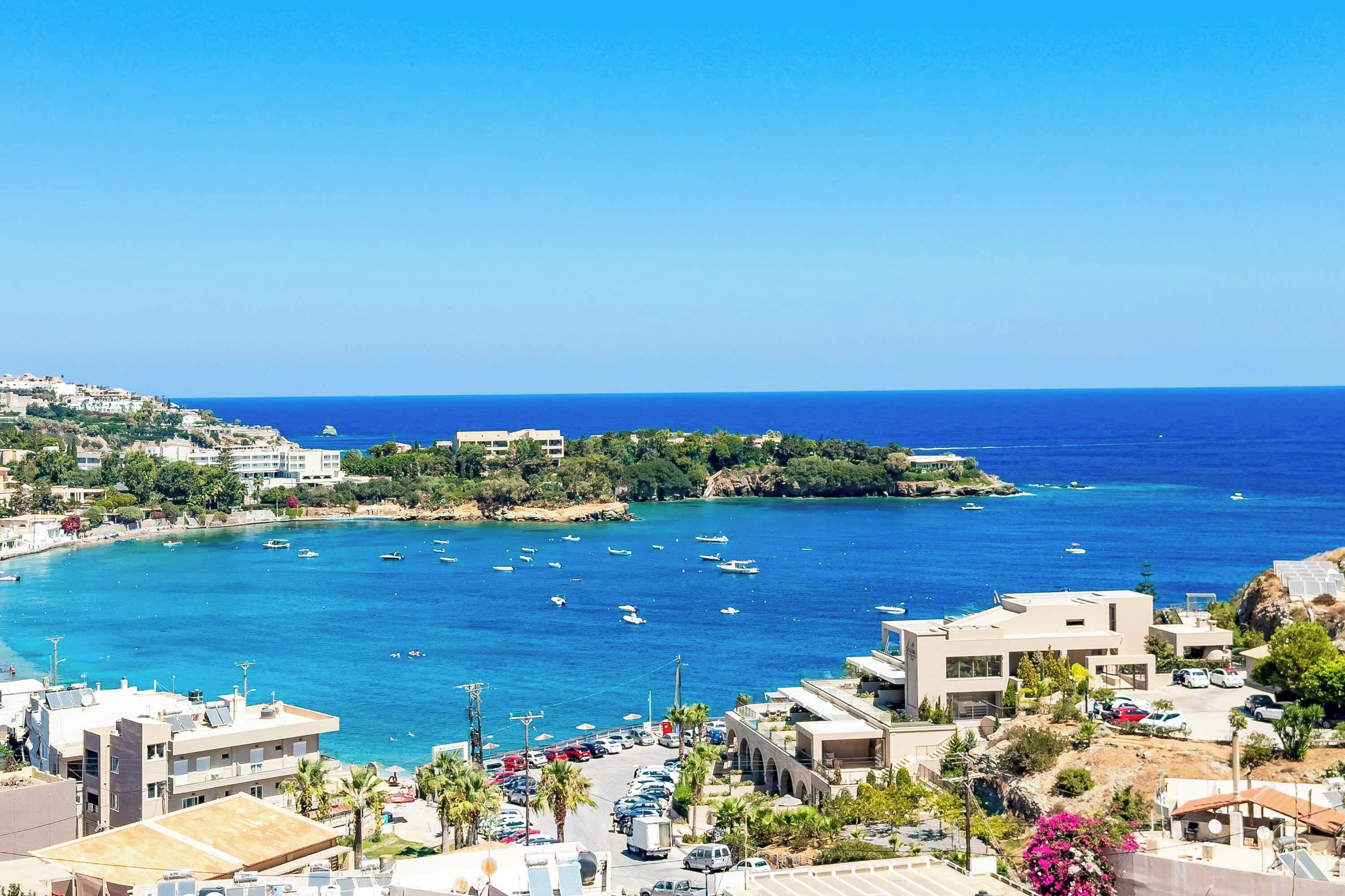 A coastal town with buildings, a marina, and clear blue waters.