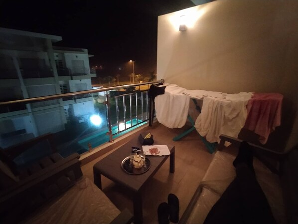 A balcony with a view of a pool, a table with a teapot, and a chair. - Apartment with a View of the Pool - CASABAY Vacation Residence (Sidi Rahal)