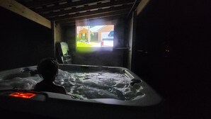 Una persona en un jacuzzi con vista a una casa a través de una abertura.