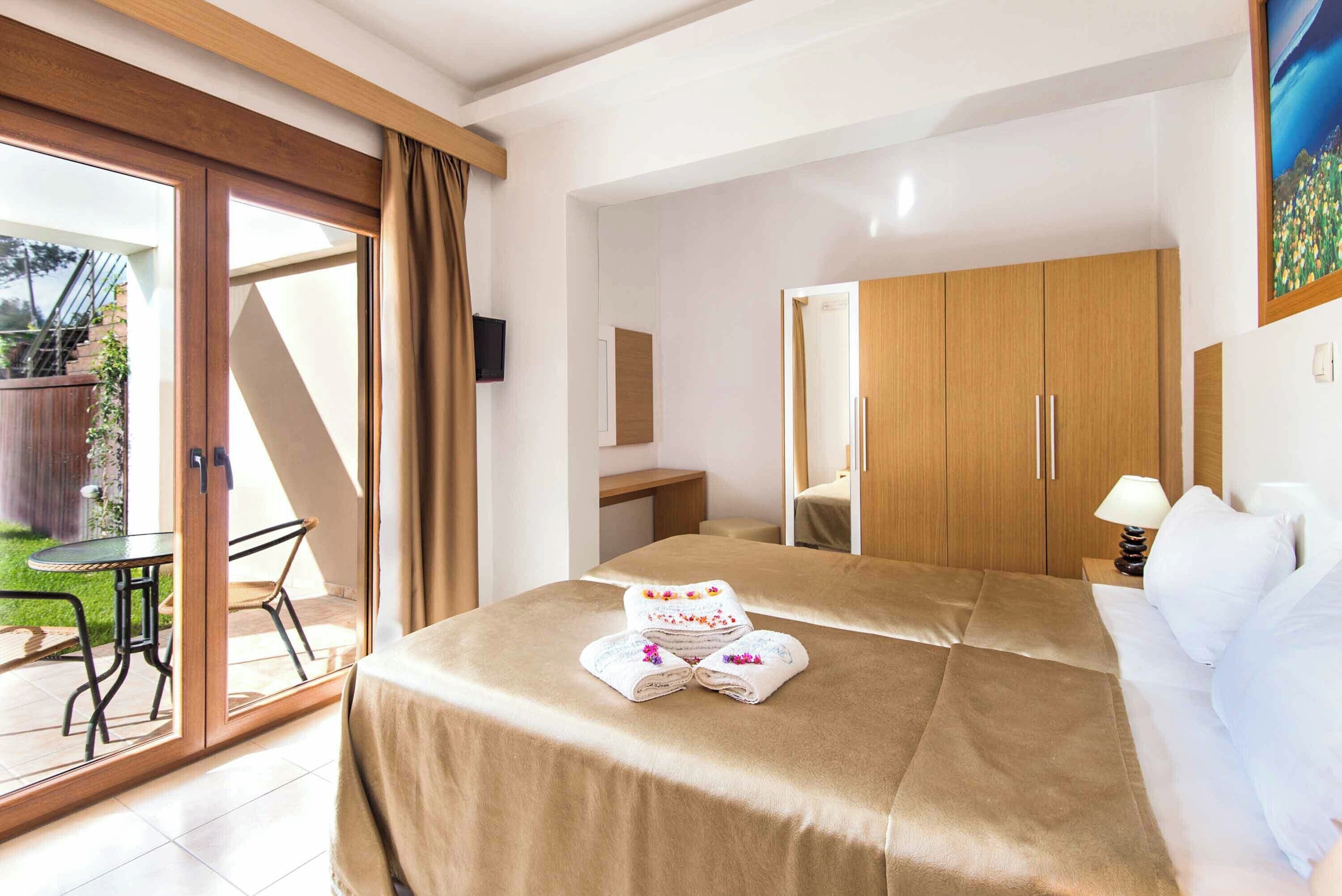 Una habitación de hotel con cama, escritorio, silla y puerta corrediza de cristal que da a un patio.
