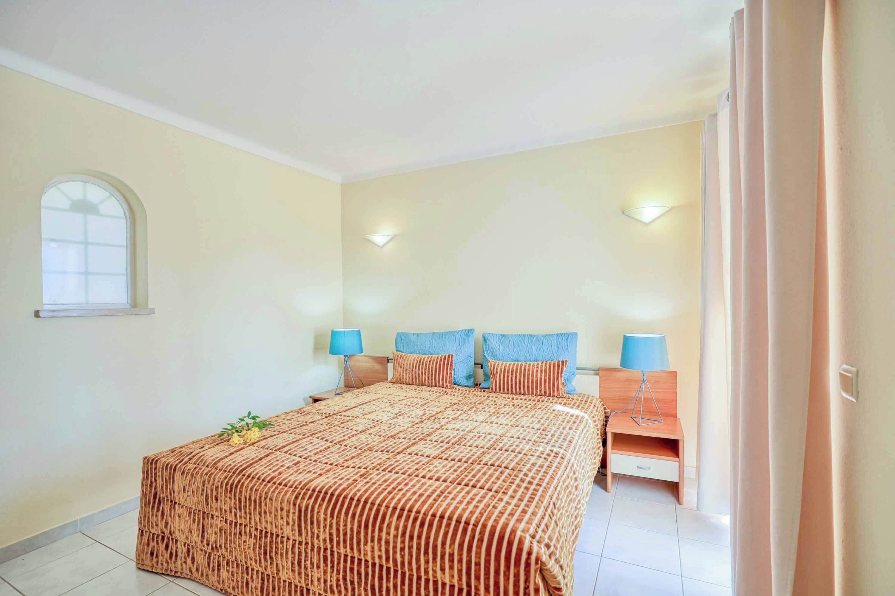 Une chambre avec un grand lit, deux tables de chevet avec des lampes, un petit bureau et une fenêtre.