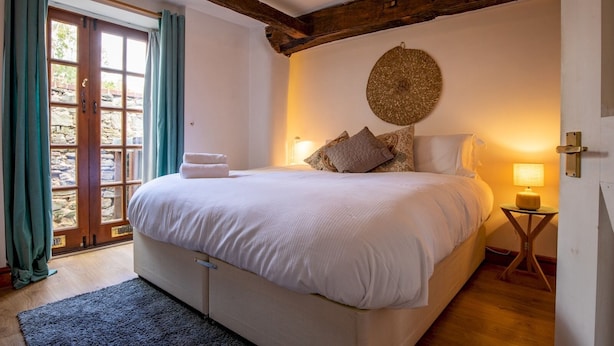 Een slaapkamer met een groot bed, een stenen muur, een houten plafondbalk en een ronde wanddecoratie.