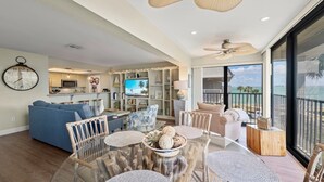 A spacious living area with a dining table, sofas, and a TV.