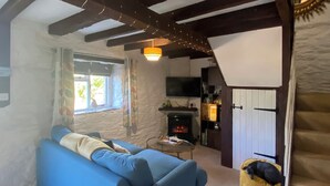 Una sala de estar acogedora con un sofá azul, una chimenea y una cama para perro.