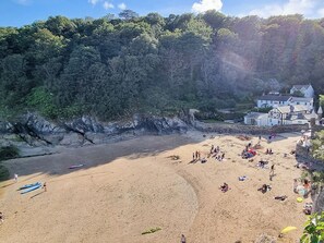 Ein Strand mit Menschen, einer Steinmauer und einem Gebäude mit weißer Fassade.
