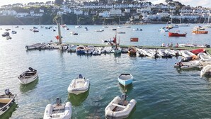 Un puerto deportivo con varios barcos amarrados, un muelle y un fondo de casas blancas en una colina.