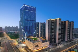 A modern high-rise building with a unique angular design, surrounded by other high-rise buildings. - Wyndham Shanwei Haifeng (Shanwei)