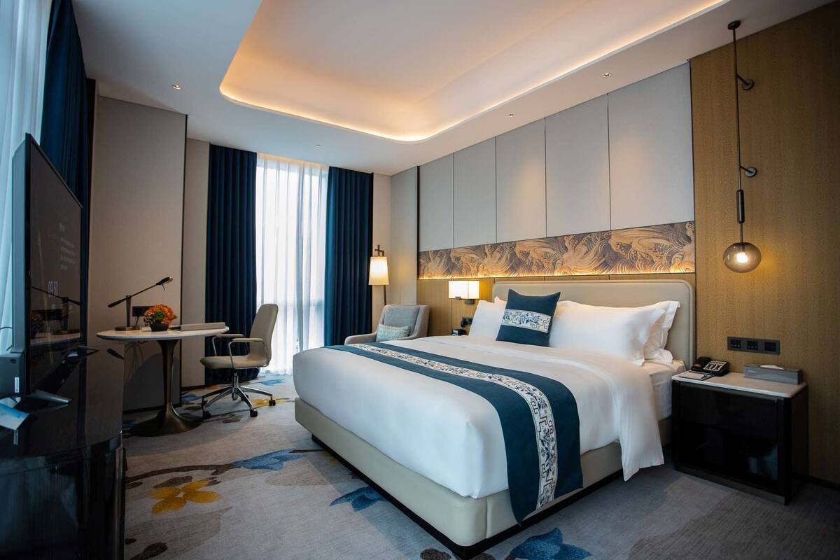 A modern hotel room with a large bed, a desk, and a chair.