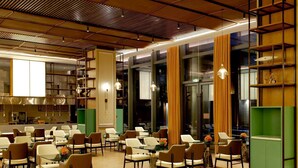 Una amplia sala de conferencias con varias mesas y sillas, ventanas grandes con cortinas y un diseño moderno en el techo.