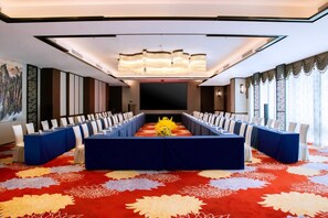 A conference room with a long table, white chairs, and a floral carpet. - Wyndham Shanwei Haifeng (Shanwei)