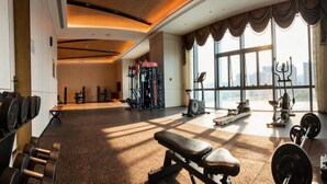 Un gimnasio con equipamiento de levantamiento de pesas, bancos y máquinas de cardio.