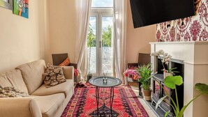 A living room with a beige sofa, a patterned rug, a TV mounted on the wall, and a fireplace. - 3 bedroom accommodation in Buxton (Buxton)