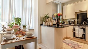 A modern kitchen with a central island, a dining area with a table set for breakfast, and a view of the outdoors through large windows. - 3 bedroom accommodation in Buxton (Buxton)