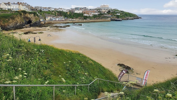 Une ville côtière dotée d’une plage de sable, d’un escalier descendant vers la plage et d’une colline où se trouvent des bâtiments.