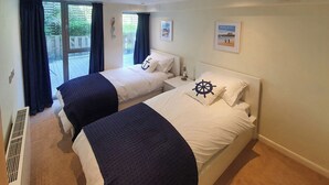 Une chambre d’hôtel avec deux lits, une grande fenêtre avec des rideaux, une vue sur l’extérieur et une petite table avec une lampe.