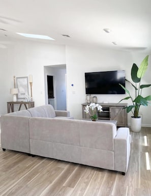Relax in this stylish living room with a large flat-screen TV, comfortable sofa, and a potted plant.