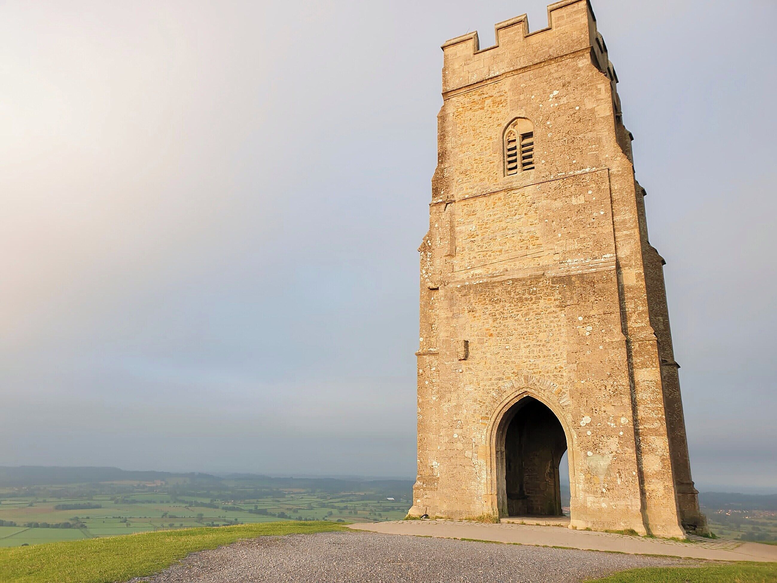 A tall, narrow stone tower with a small arched entrance and a window near the top.