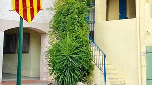 Ein Gebäude mit gelber Fassade, einem grünen Vordach und einer Flagge.