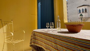 Ein Tisch mit einer gestreiften Tischdecke, zwei Weingläsern, einer Flasche und einem Terrakottatopf.