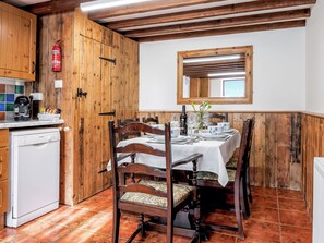 A wooden interior with a dining table set for four, a Bosch dishwasher, and a fire extinguisher. - Holly Lodge - UK36321 (Holly Hedge Farm)