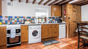 A kitchen with wooden cabinets, a stove, a washing machine, and a dishwasher. - Holly Lodge - UK36321 (Holly Hedge Farm)