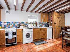 A kitchen with wooden cabinets, a stove, a washing machine, and a dishwasher. - Holly Lodge - UK36321 (Holly Hedge Farm)