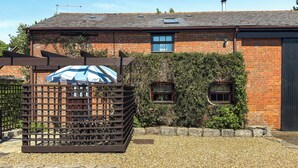 A brick building with a sloped roof, a wooden gate, and a gravel driveway. - Holly Lodge - UK36321 (Holly Hedge Farm)
