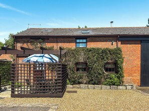 A brick building with a sloped roof, a wooden gate, and a gravel driveway. - Holly Lodge - UK36321 (Holly Hedge Farm)