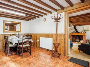 Un comedor con una mesa de madera dispuesta para cuatro personas, un espejo y un perchero.