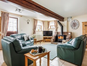 Ein gemütliches Wohnzimmer mit Kamin, Ledersofas und einem Fernseher.