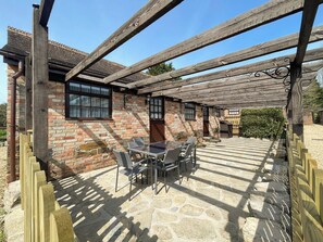 A stone patio with a wooden pergola and outdoor seating. - Robins Nest - UK36322 (Holly Hedge Farm)