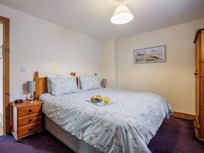 A bedroom with a bed, wooden nightstand, and a bedside table with a lamp. - Robins Nest - UK36322 (Holly Hedge Farm)