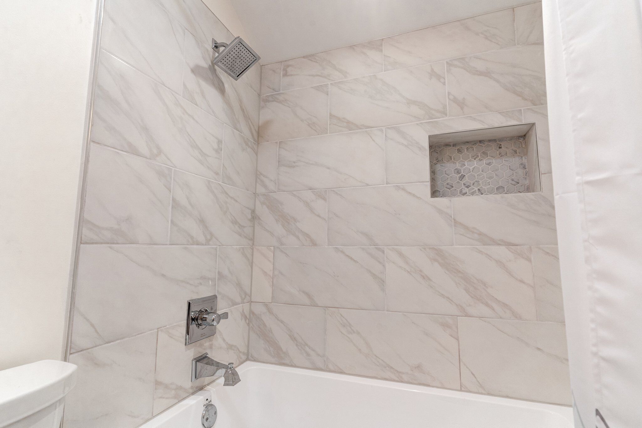 A bathroom with a bathtub, a showerhead, and a toilet.