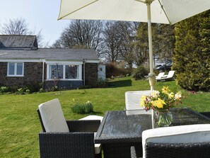 A patio area with wicker furniture, a table, and a white umbrella. - 2 bedroom accommodation in Winsford (Winsford)