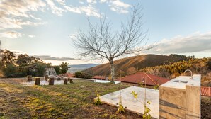 A cemetery with headstones, a large tree, and a building with a red roof. - CASA DO RANCHO (Amares)