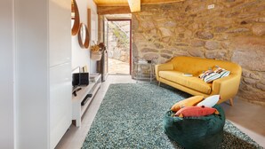 A modern living room with a stone wall, a yellow sofa, a green bean bag, and a wooden ceiling. - CASA DO RANCHO (Amares)